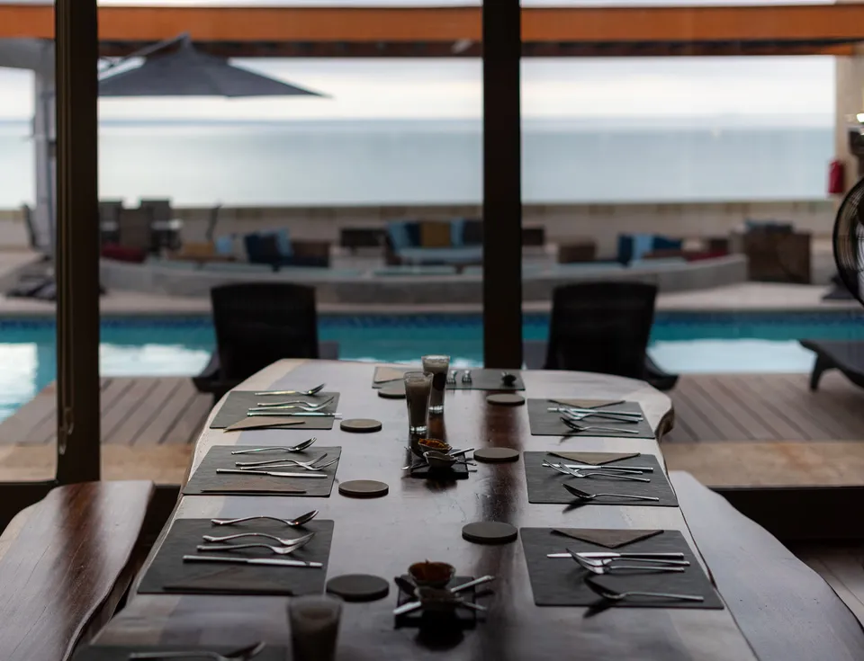Dining table looking toward a pool and outdoor lounge at Ambio's Mexico residence