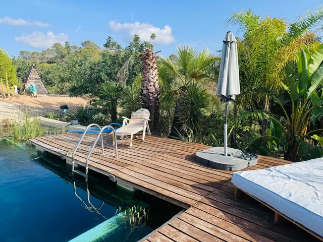Garden pool and wooden sun deck with loungers at Harambe in the Valencia countryside