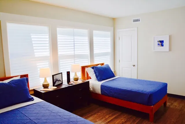 Shared bedroom at Jackson House, with two beds, blue bedding and a bedside table.