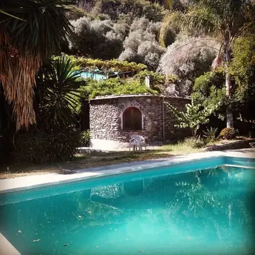 Pool beside a small stone building and garden at Madera Sagrada.