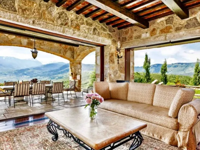 Stone-walled lounge opening onto a mountain-view terrace, shown in Mercui's Recovery.com listing