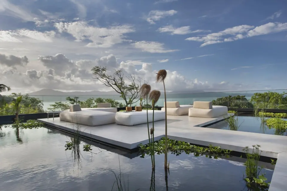 Outdoor lounge surrounded by water and planting, overlooking the coast, on the Florianópolis program page.