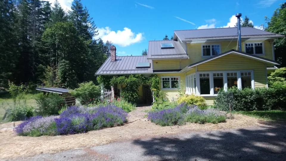 Yellow farmhouse and flower garden at Rooted Waters on Salt Spring Island.